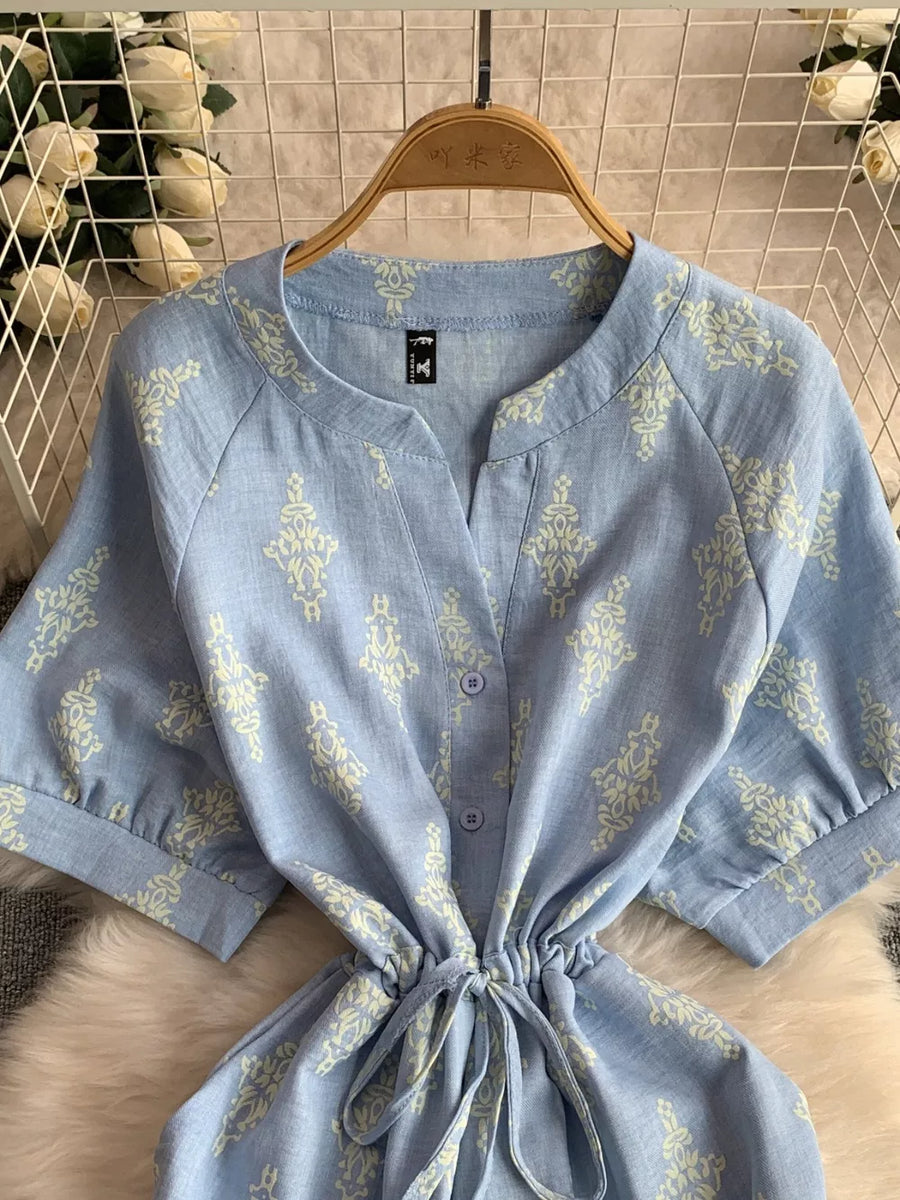 Blue patterned drawstring jumpsuit with short sleeves and button front.