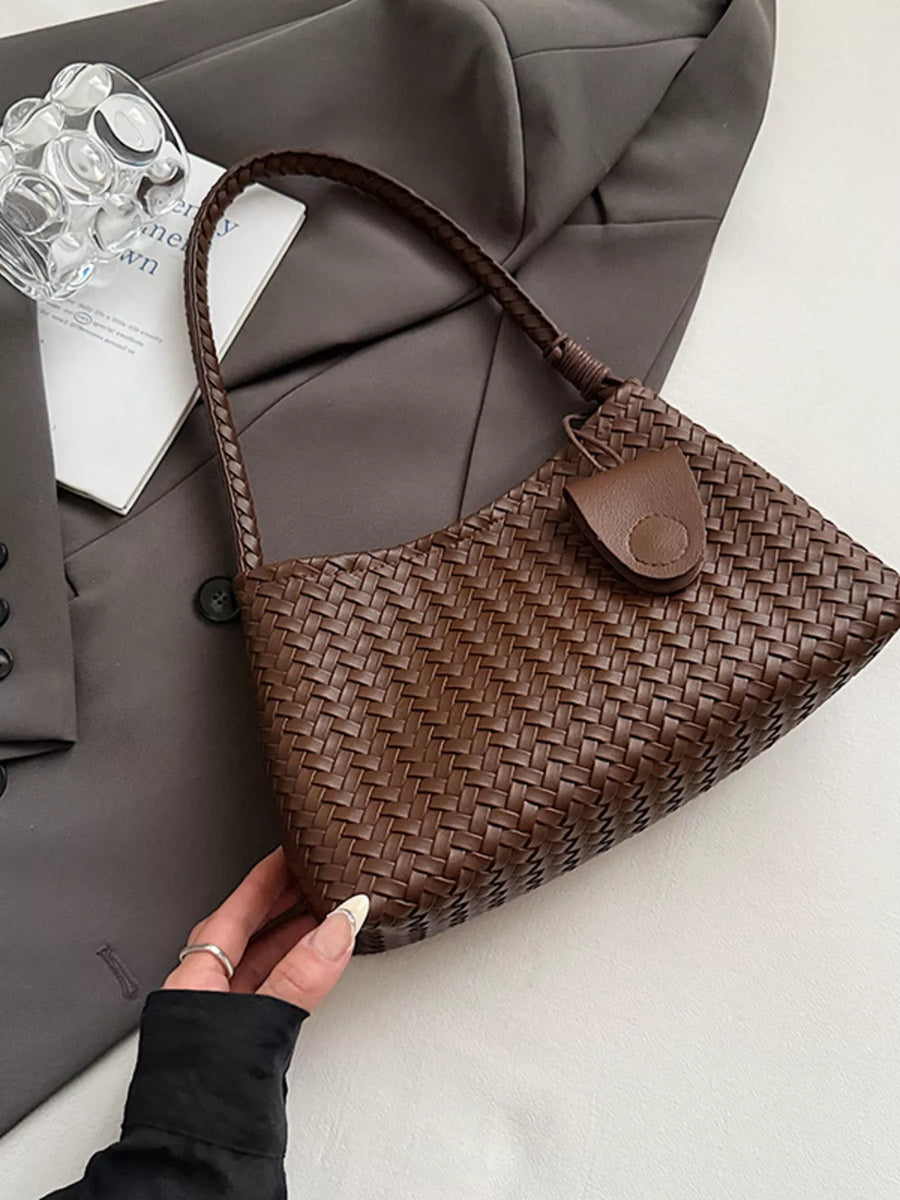 Woven shoulder bag in coffee color with braided strap and leather tab closure.