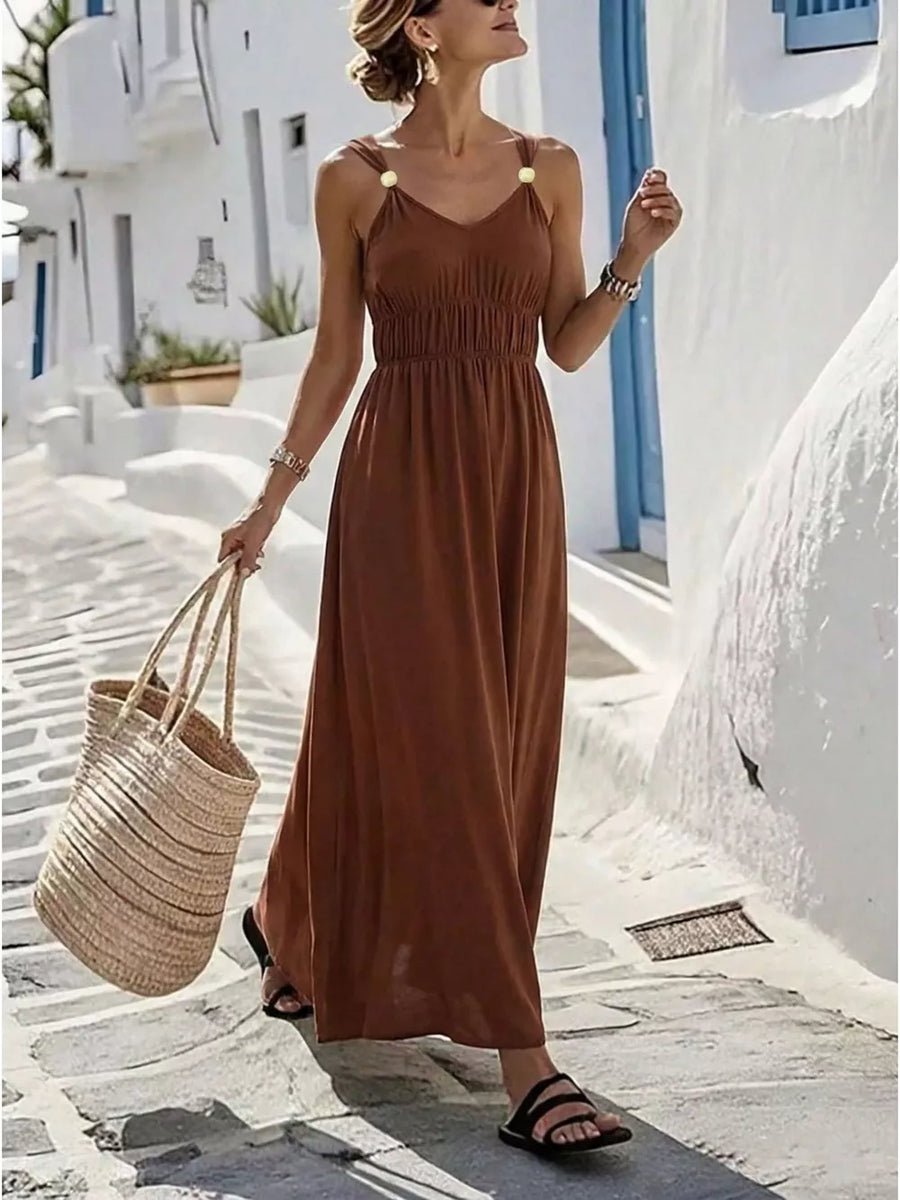 Brown V-neck sleeveless maxi dress with smocked waist and gold detail straps.