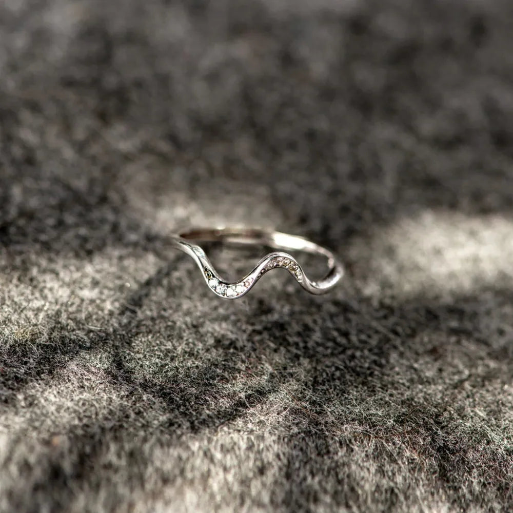 Serpentine diamond contour ring in silver with a wavy design and small clear stones.