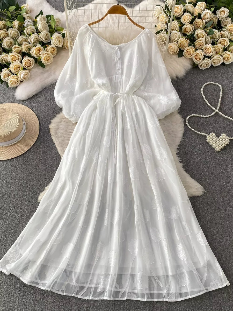 White chiffon maxi dress with floral embroidery, balloon sleeves, and a belted waist.