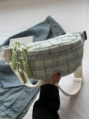 Textured tweed belt bag in light green with braided pulls and a white strap.