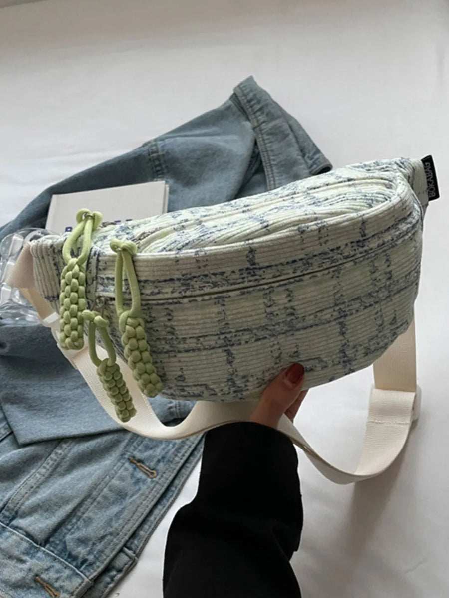 Textured tweed belt bag in light green with braided pulls and a white strap.