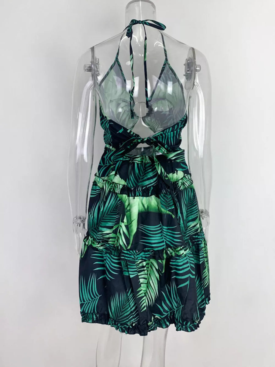 Halter mini dress with abstract leaf print in dark green and black, featuring a cutout back and tiered skirt.