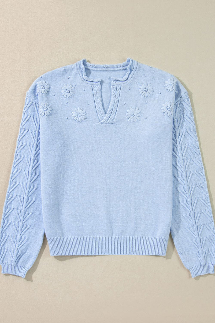 Light blue sweater with floral applique and cable knit sleeves