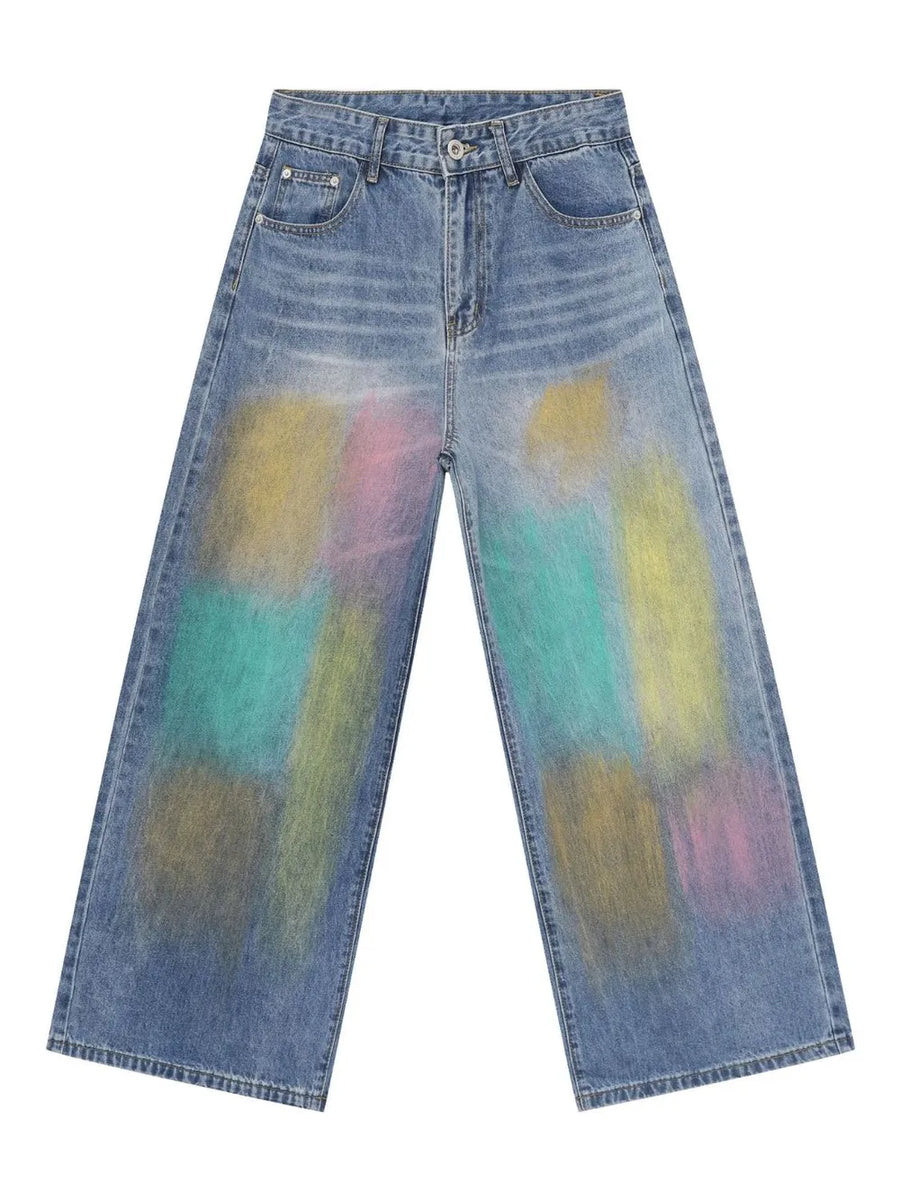 Graffiti wash wide leg denim trousers in medium blue with colorful abstract paint splatters.