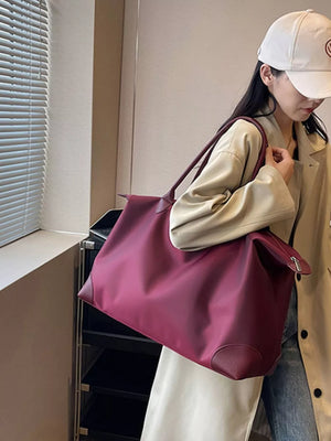 Burgundy Oxford cloth travel tote bag with leather trim and shoulder straps.