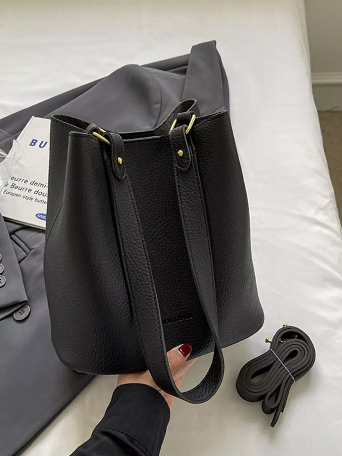 Black pebbled leather tote bag with gold hardware and adjustable strap