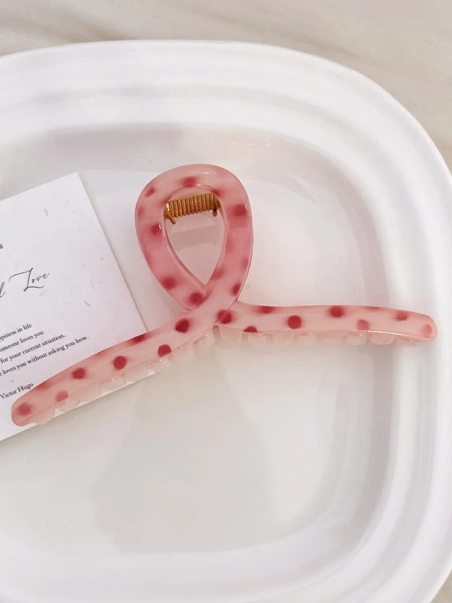 Polka dot claw hair clip in pink with red dots.