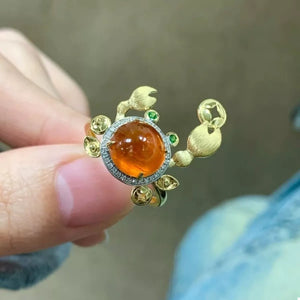 Gold crab ring with orange gemstone and green accents, artisan piece.
