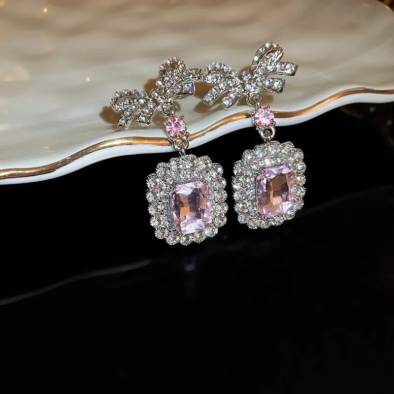 Silver bow crystal drop earrings with pink accents and rectangular pink gems.