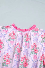 Floral tiered ruffle dress with pink roses and bows on a light pink polka dot background.