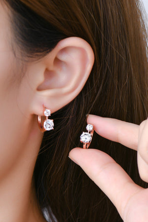 Rose gold huggie hoop earrings with two clear stones each.