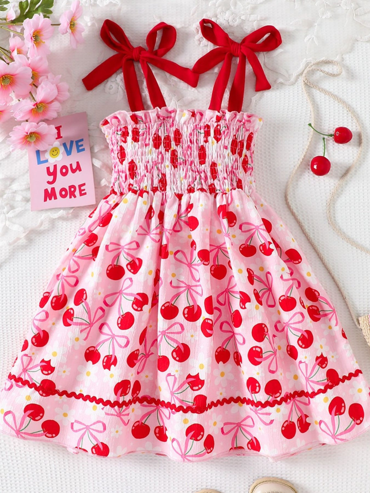 Pink cherry print smocked toddler dress with red bow straps and ruffled hem