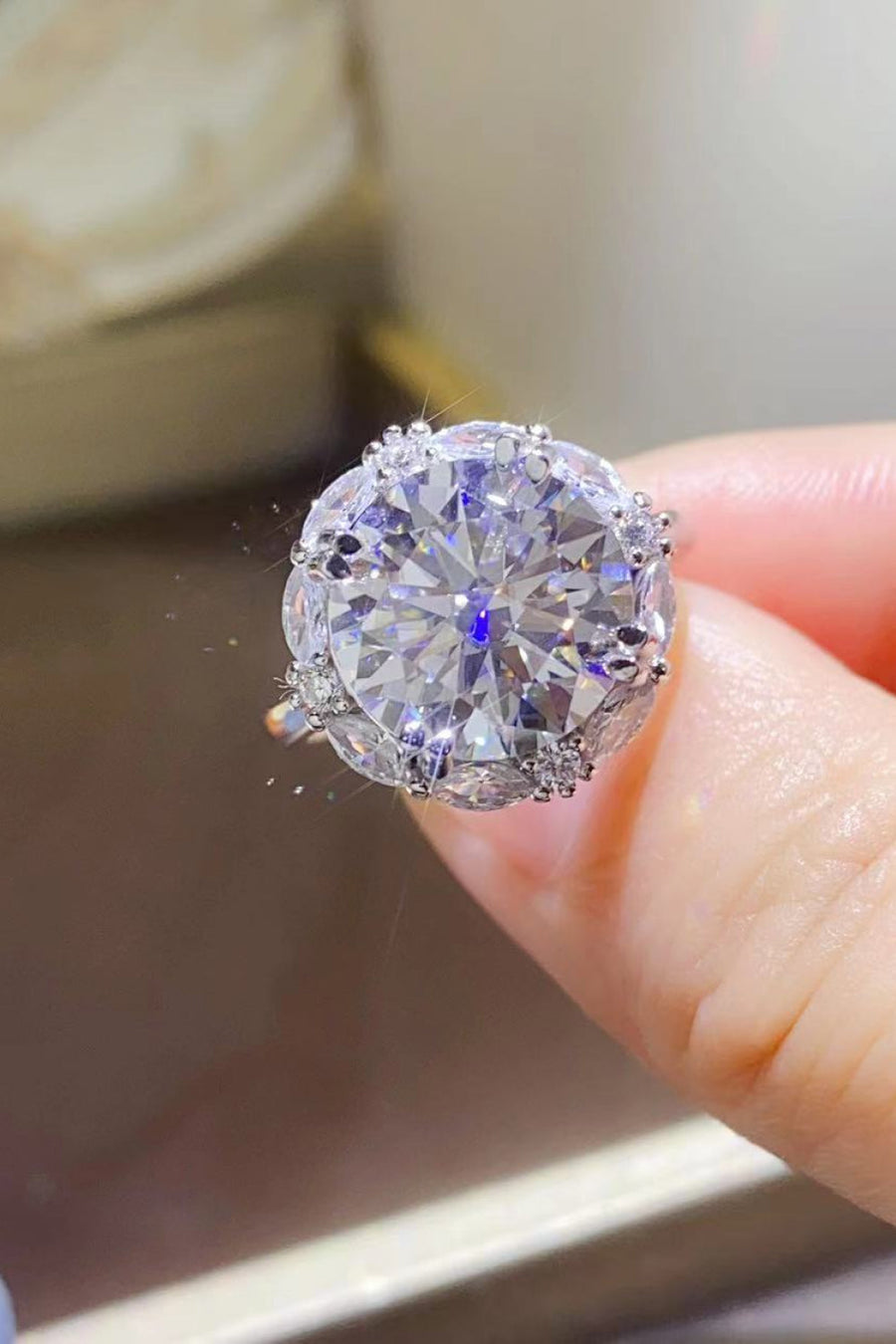 Silver moissanite halo ring with a large round center stone and smaller accent stones.