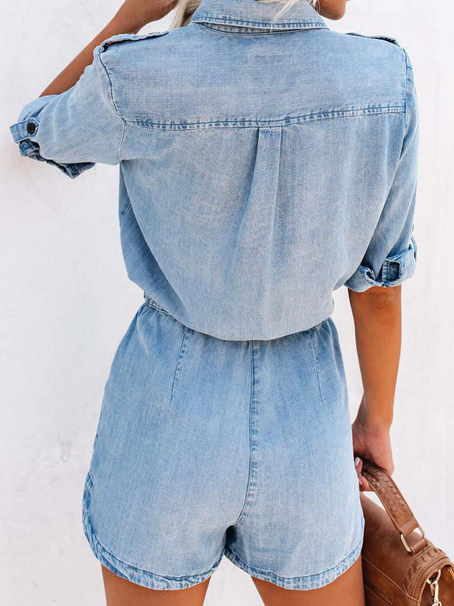 Light wash denim romper with shirred waist and buttoned short sleeves.