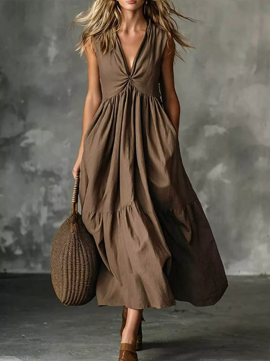 Brown linen maxi dress with knotted V-neck, sleeveless, tiered skirt, and pockets.