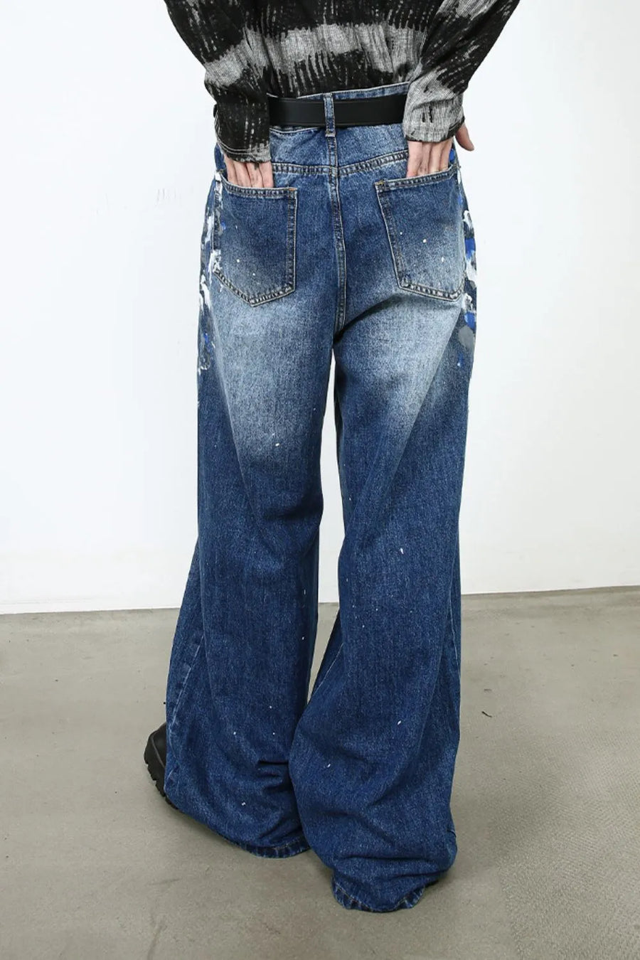 Painterly denim palazzo trousers in medium wash with artistic paint splatters and wide leg.
