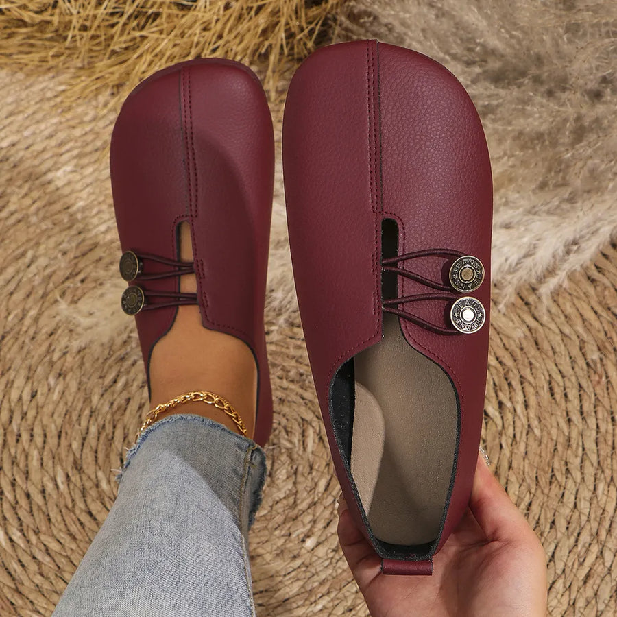 Burgundy leather slip-on flats with antique gold button detail and elastic straps.
