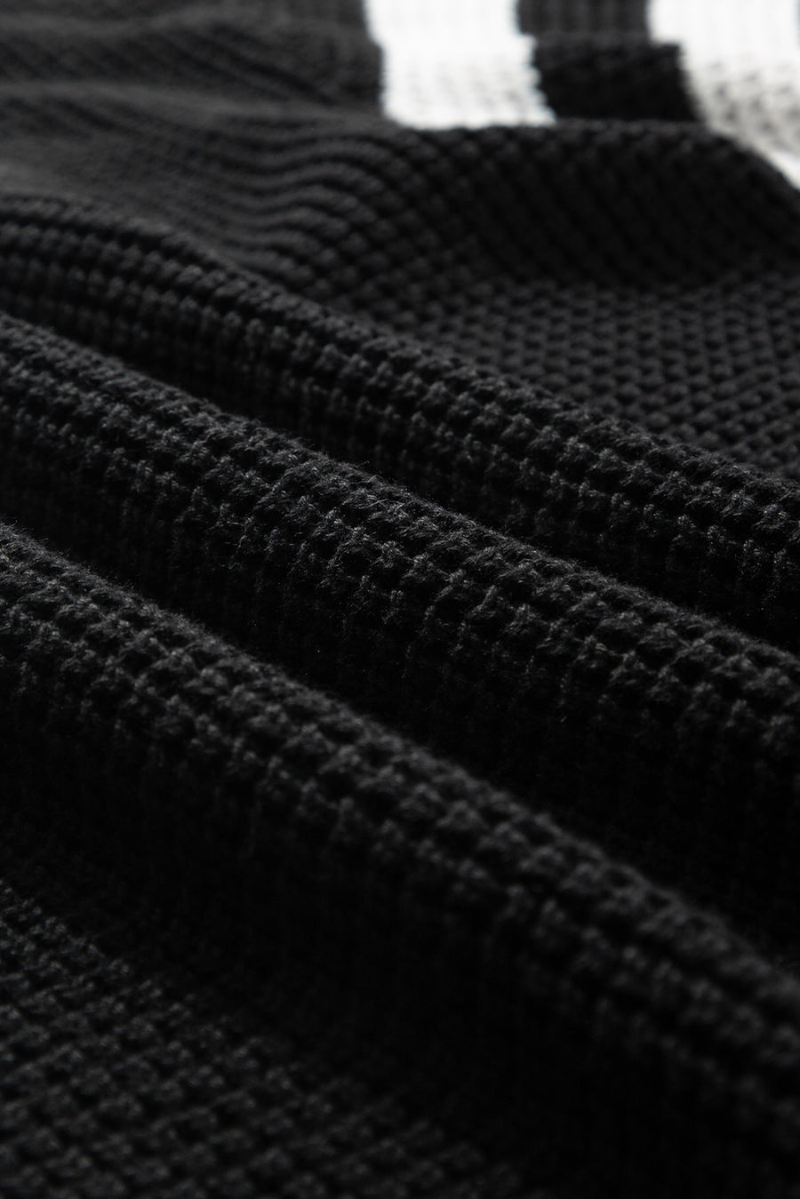 Black knit turtleneck sweater with checkerboard and stripe sleeves