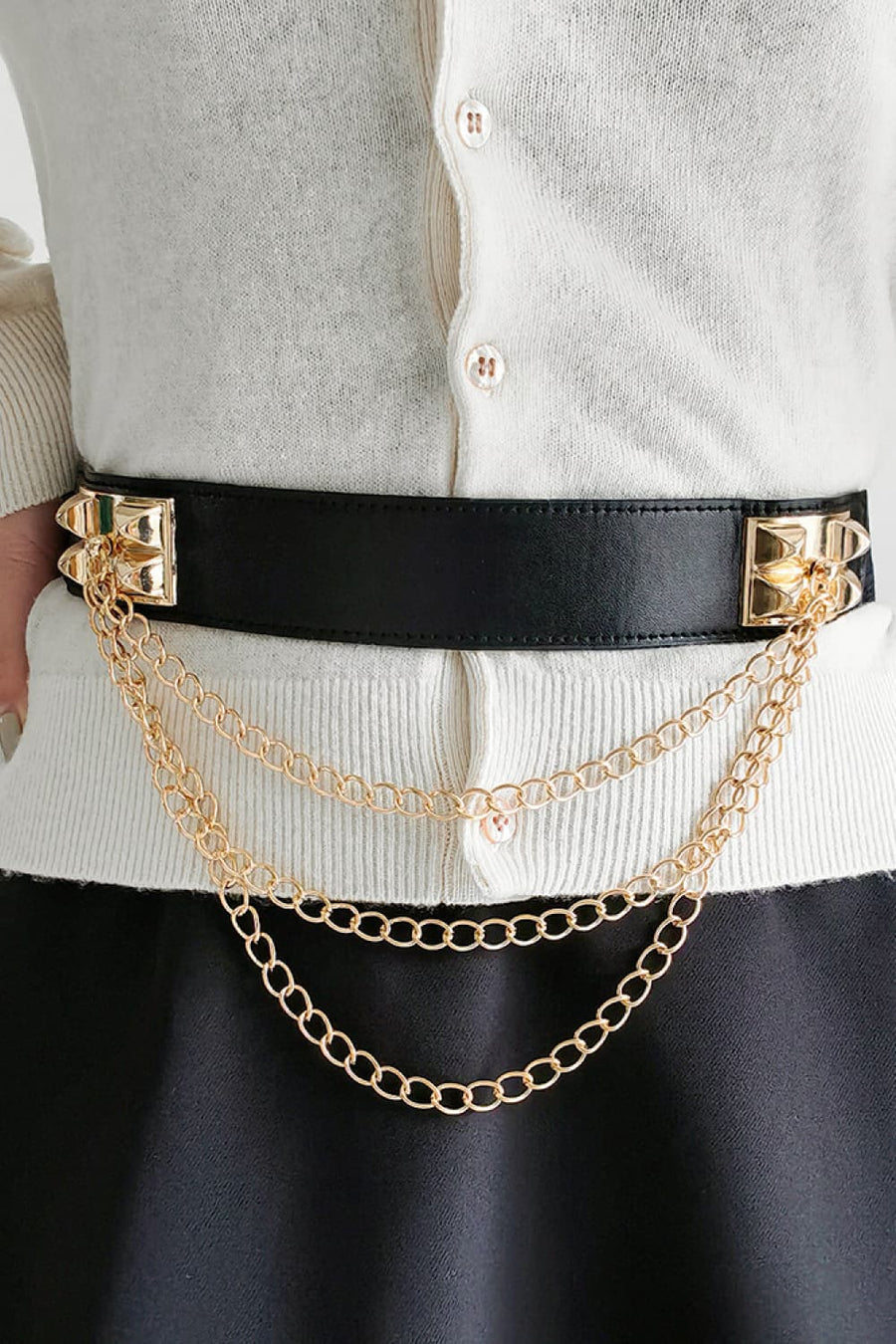 Black leather belt with gold spiked hardware and layered chain drape detail.