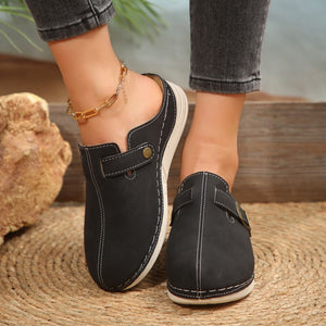 Black slip-on flats with buckle detail and contrast stitching.