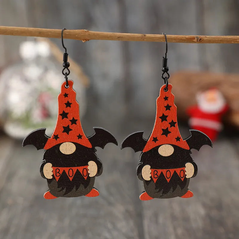 Black wood gnome drop earrings with bat wings and orange star hats.