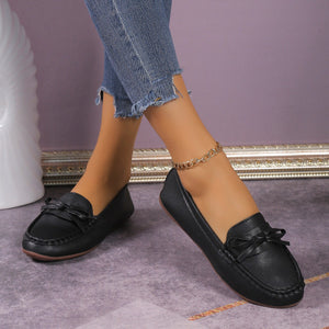 Black bow embellished flat slip-on loafers with a gold chain anklet.