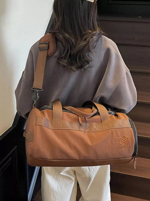 Brown Oxford cloth duffel bag with carry handles and adjustable strap.