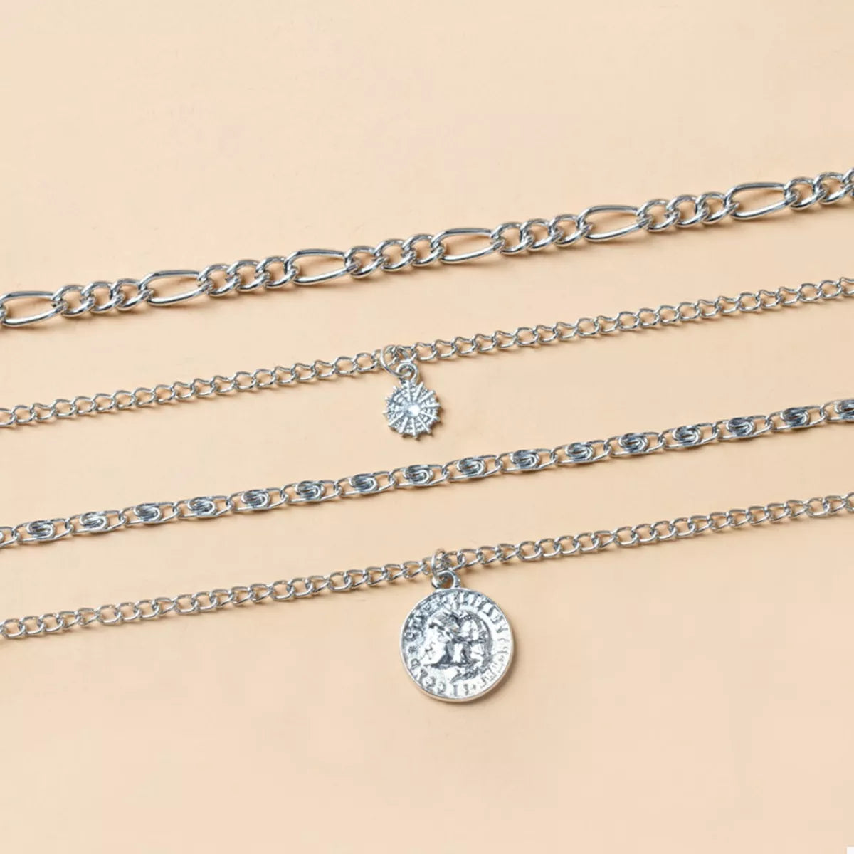 Layered silver necklaces with coin and starburst pendants