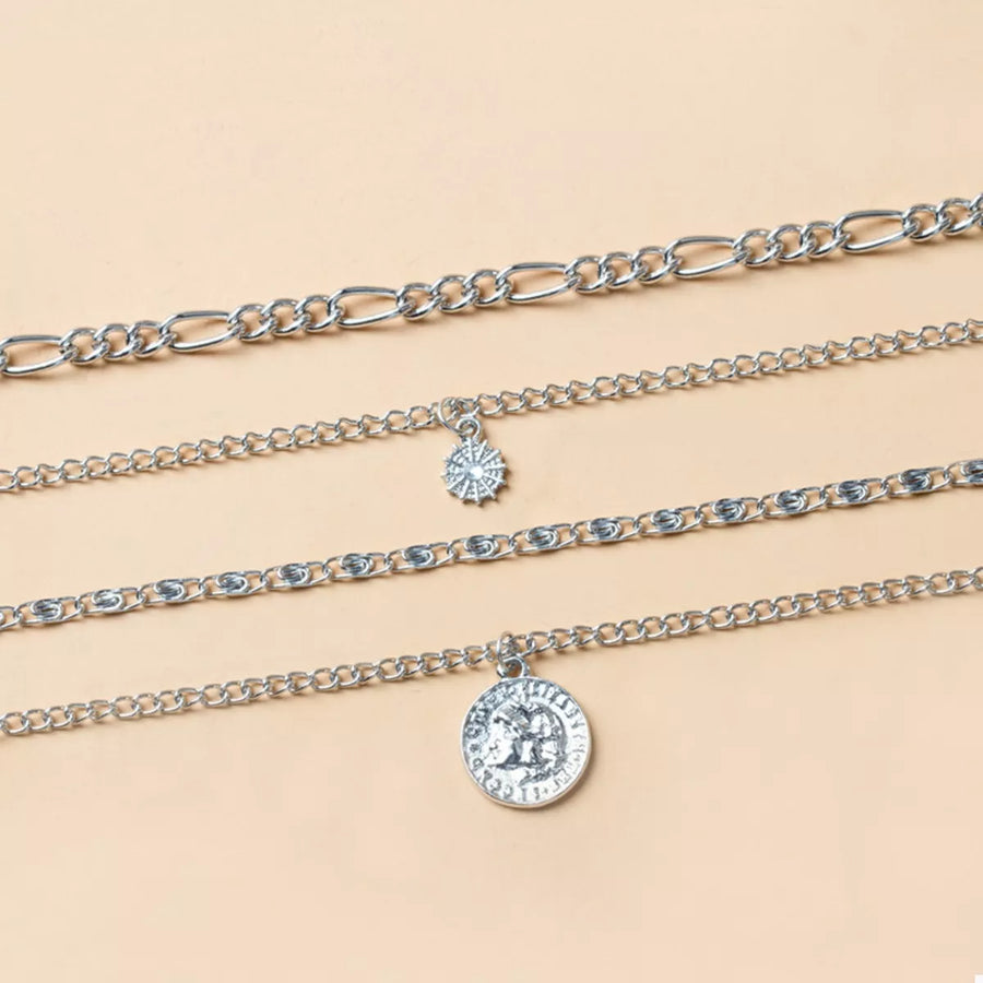 Layered silver necklaces with coin and starburst pendants