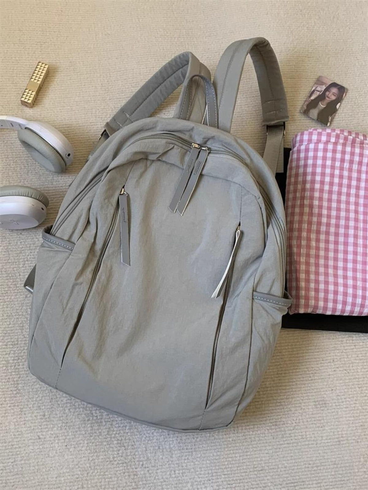 Light gray lightweight nylon backpack with multiple zippered pockets and adjustable straps.