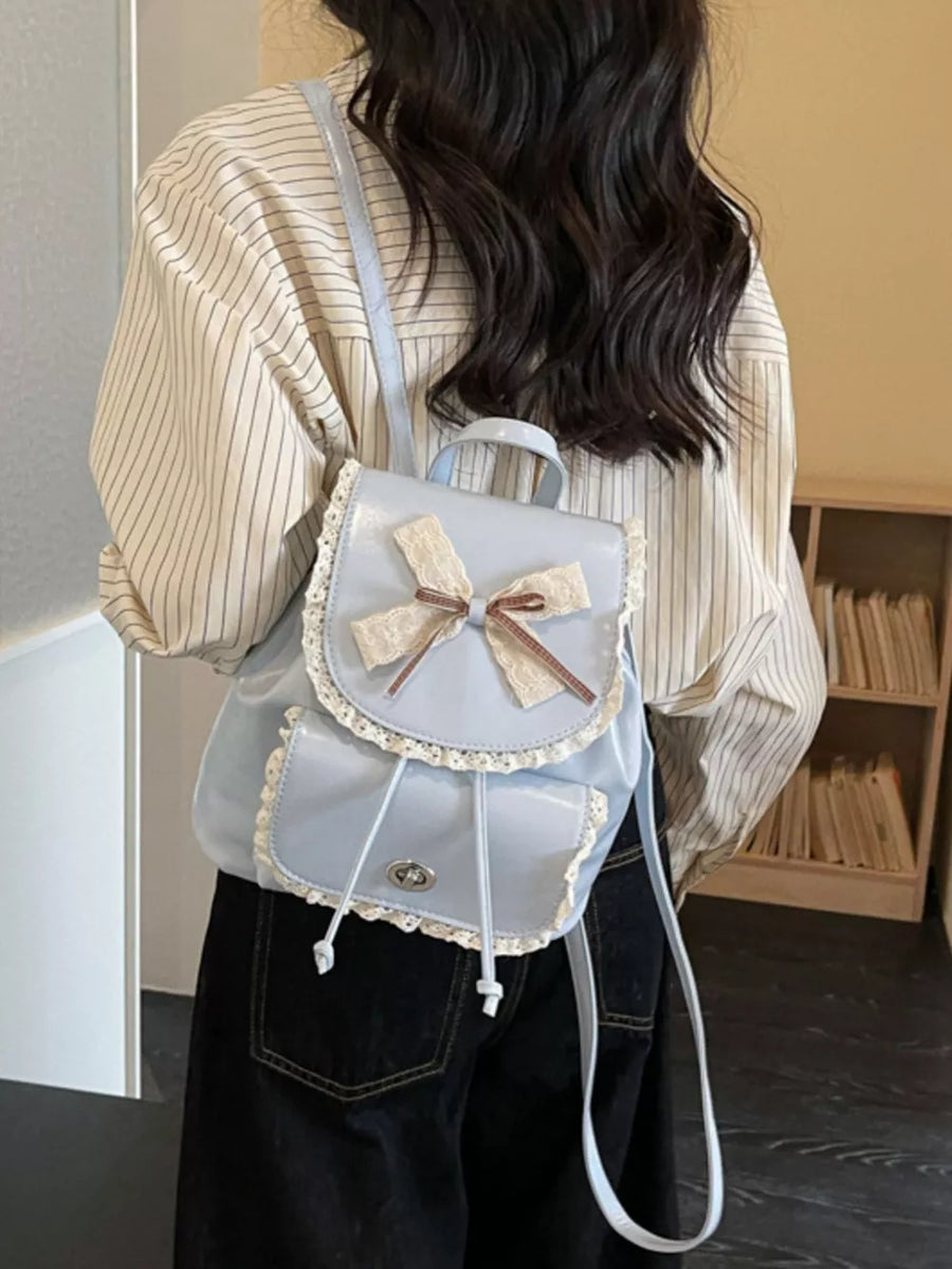 Blue mini backpack with lace trim and bow detail.
