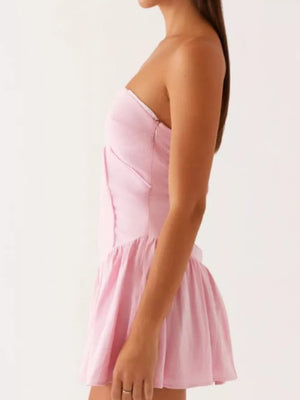 Blush pink ruffled tube dress with a gathered skirt and side tie detail.