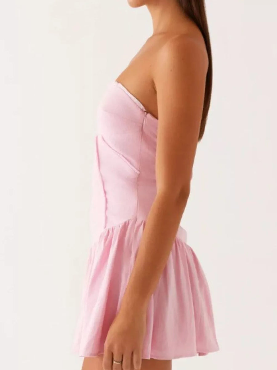 Blush pink ruffled tube dress with a gathered skirt and side tie detail.