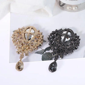 Regal teardrop embellished brooch in gold and black alloy with clear crystal accents.