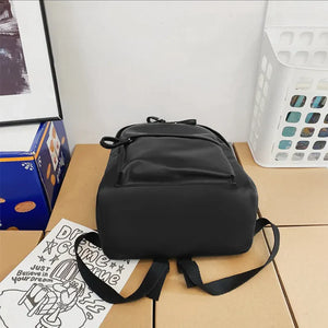 Black leather backpack with front pocket and adjustable straps.