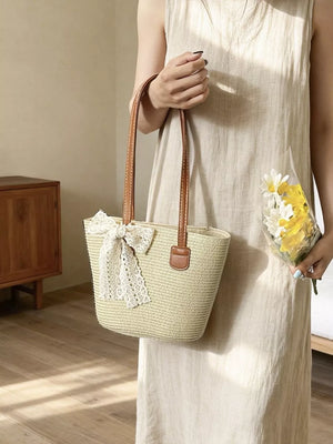 Charming straw shoulder bag with lace bow detail and leather straps.