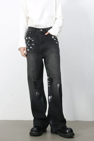 Painterly distressed wide-leg jeans in dark wash denim with artistic brushstroke details and ripped accents.