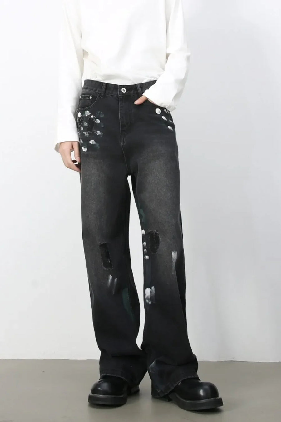 Painterly distressed wide-leg jeans in dark wash denim with artistic brushstroke details and ripped accents.
