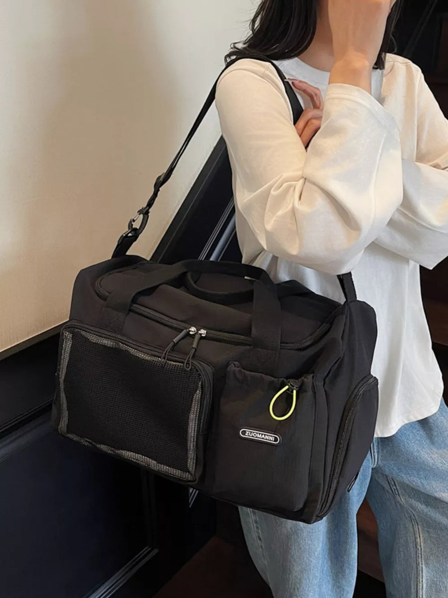 Black duffel bag with mesh pocket and yellow drawstring detail, worn over the shoulder.