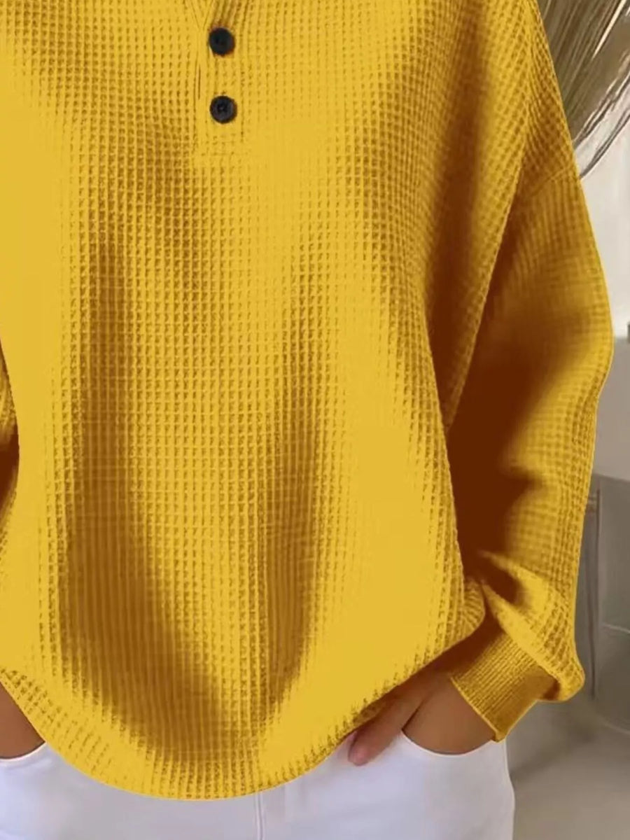 Yellow waffle knit top with button detail and long sleeves.