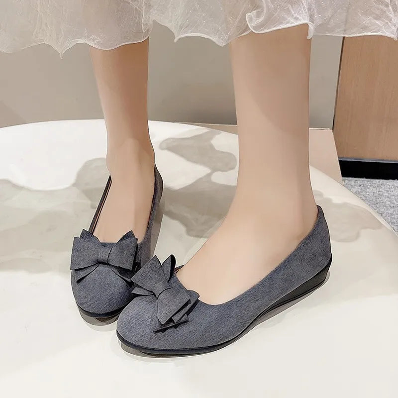 Dark gray suede ballet flats with bow embellishment.
