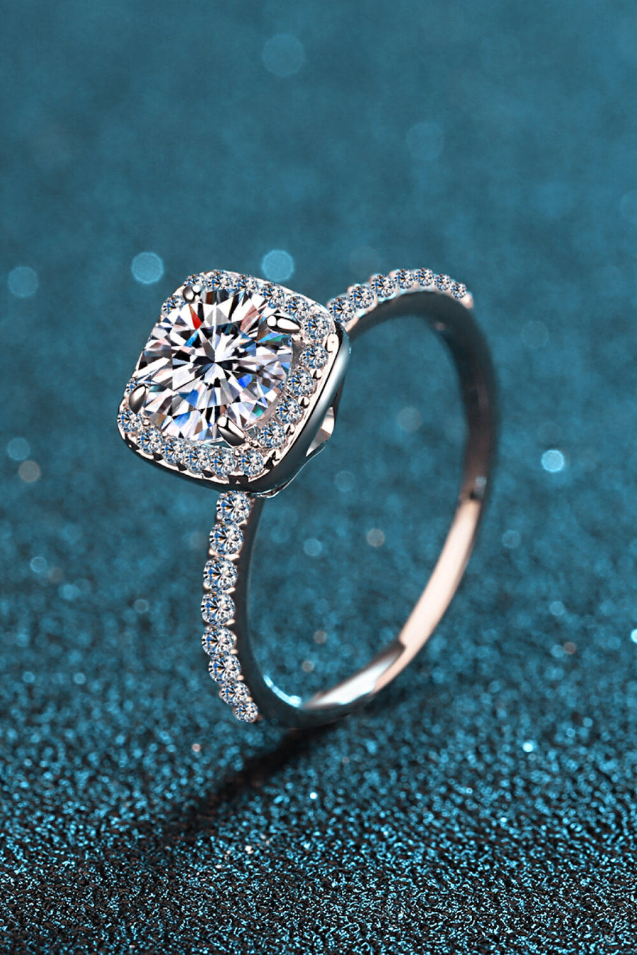Cushion halo engagement ring in silver with pave band and center stone.