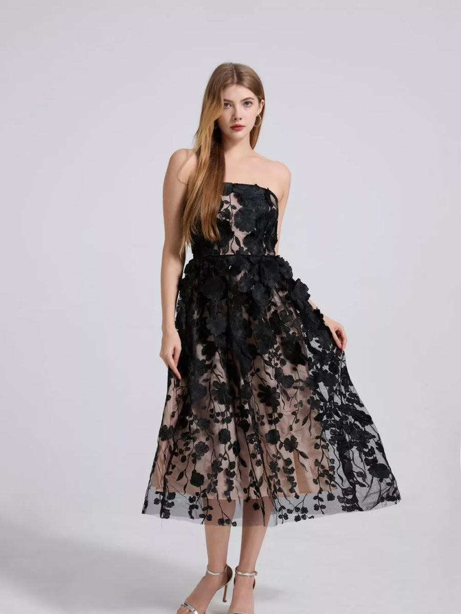 Black midi dress with intricate floral applique, strapless neckline, and sheer overlay.