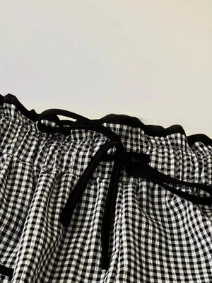 High-waisted wide-leg gingham pants with black tie detail and ruffled waist.