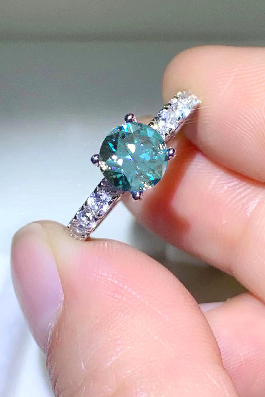 Celestial teal moissanite ring with pavé diamond band.