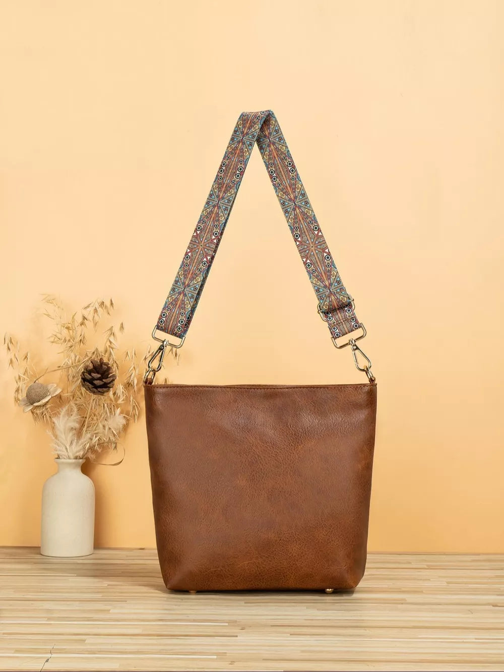 Tan pu leather crossbody bag with a colorful geometric strap.