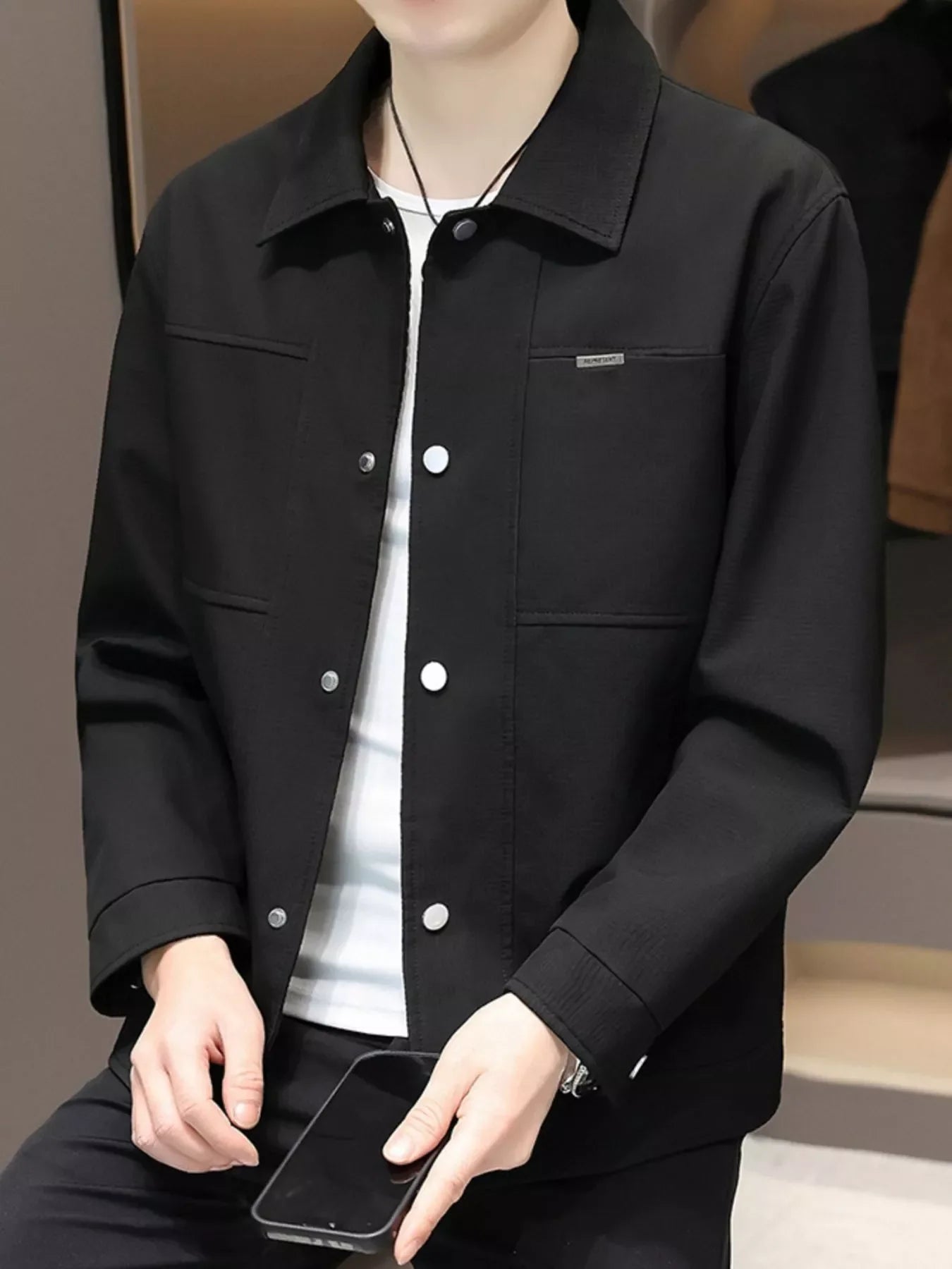 Men's black snap down jacket with chest pocket detail and white snaps.