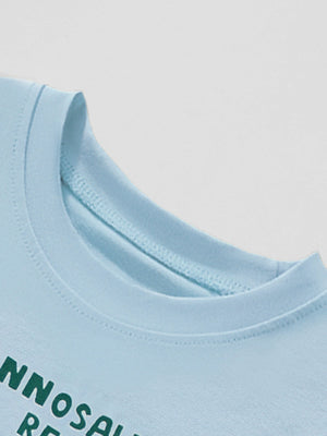 Light blue cotton t-shirt with green text graphic and crew neck.